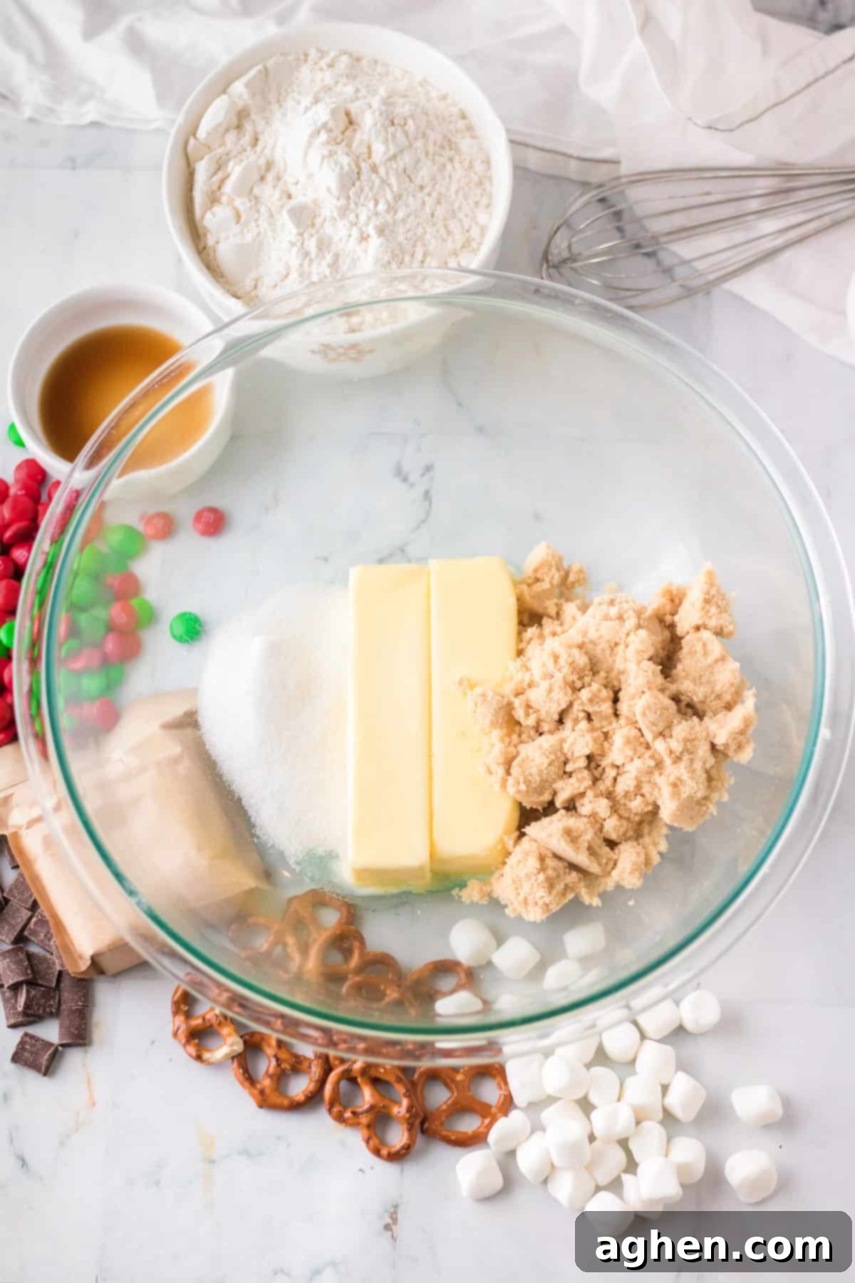 A glass mixing bowl holds softened butter, granulated sugar, and light brown sugar, ready to be creamed together for Christmas kitchen sink cookies.