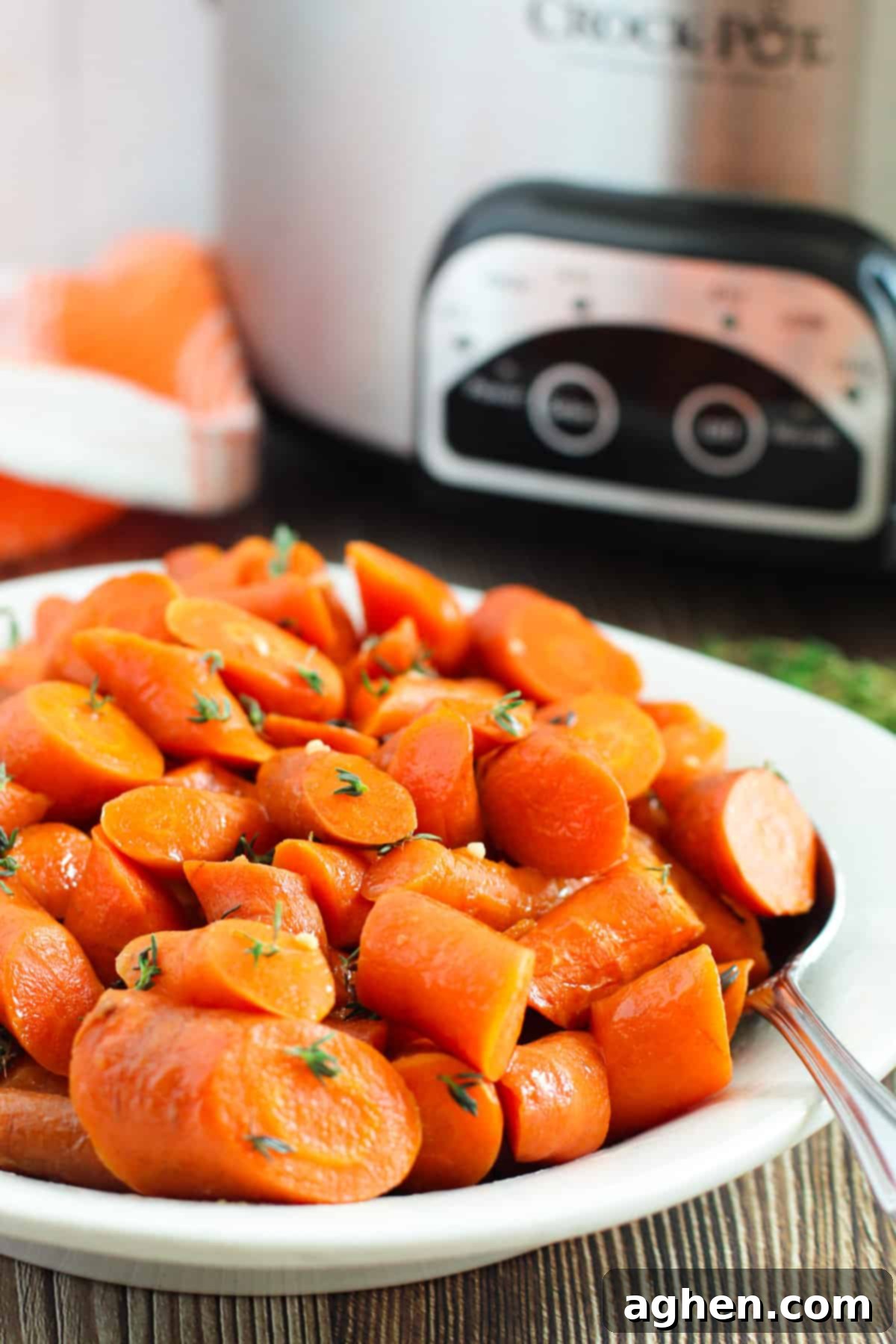 Brown sugar glazed carrots in a slow cooker, with the pot in the background.
