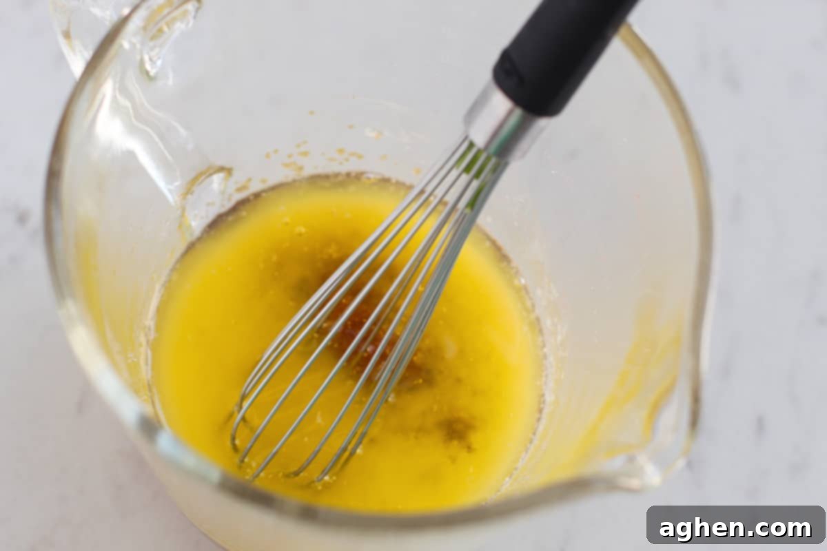 Butter, brown sugar, garlic, and salt being whisked together in glass measuring cup to form the glaze.