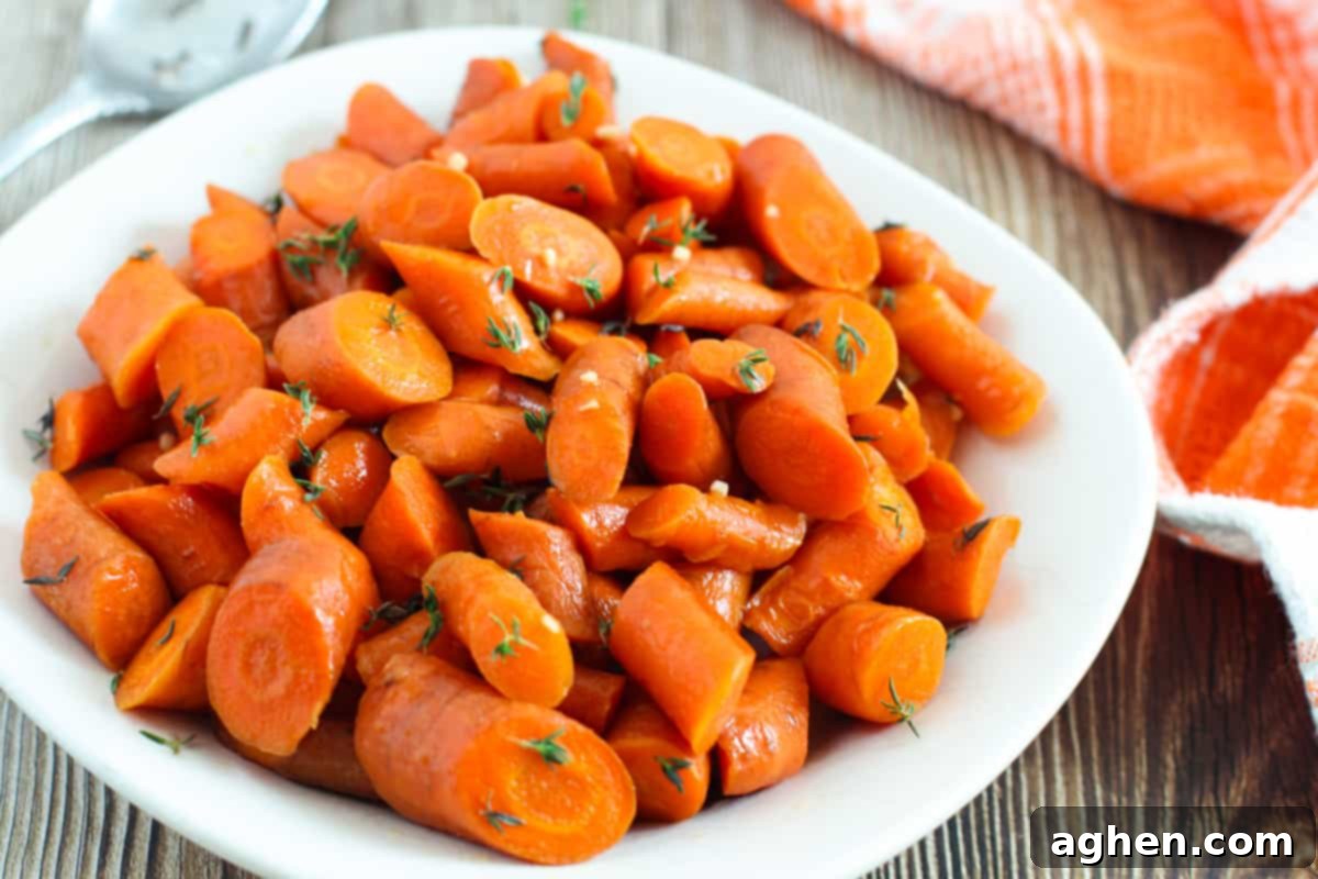 Slow cooker glazed carrots on white plate, garnished with fresh herbs.