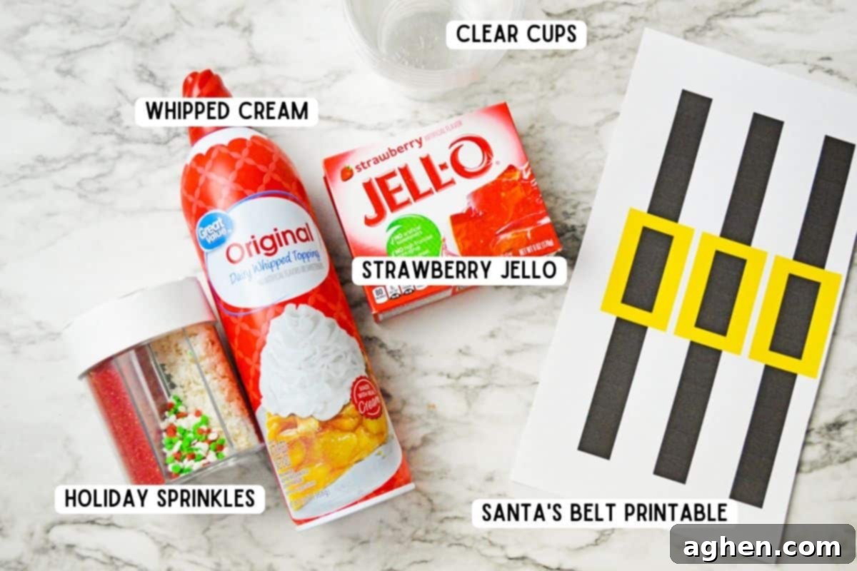 Jolly Santa Jello Cups 3 Assortment of ingredients for Santa Jello Cups: Christmas sprinkles, a box of Strawberry Jello, a can of whipped cream, clear plastic cups, and paper with Santa belt designs.