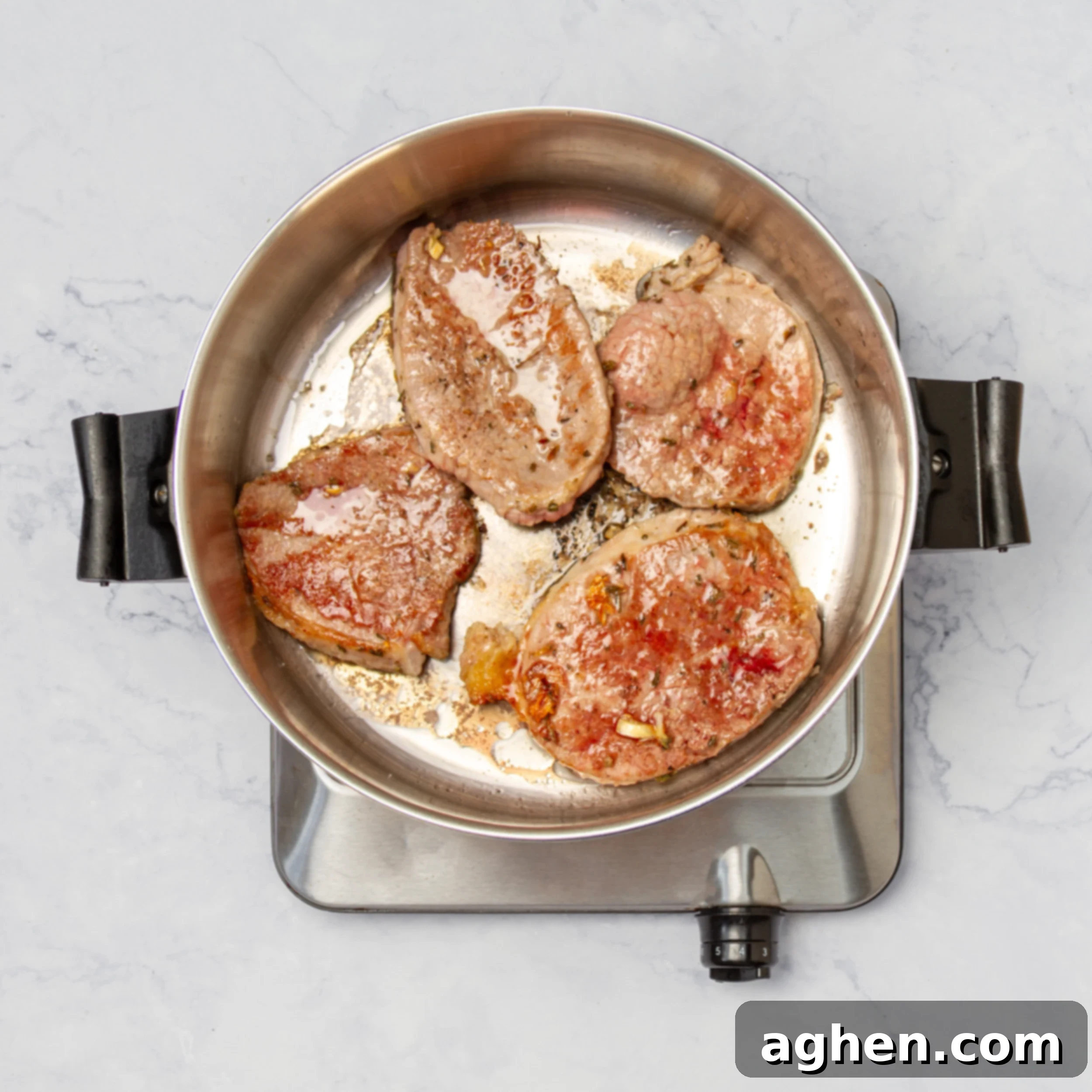 Seasoned beef slices browning in a hot skillet with olive oil, developing a golden crust for the Swiss Steak dish.