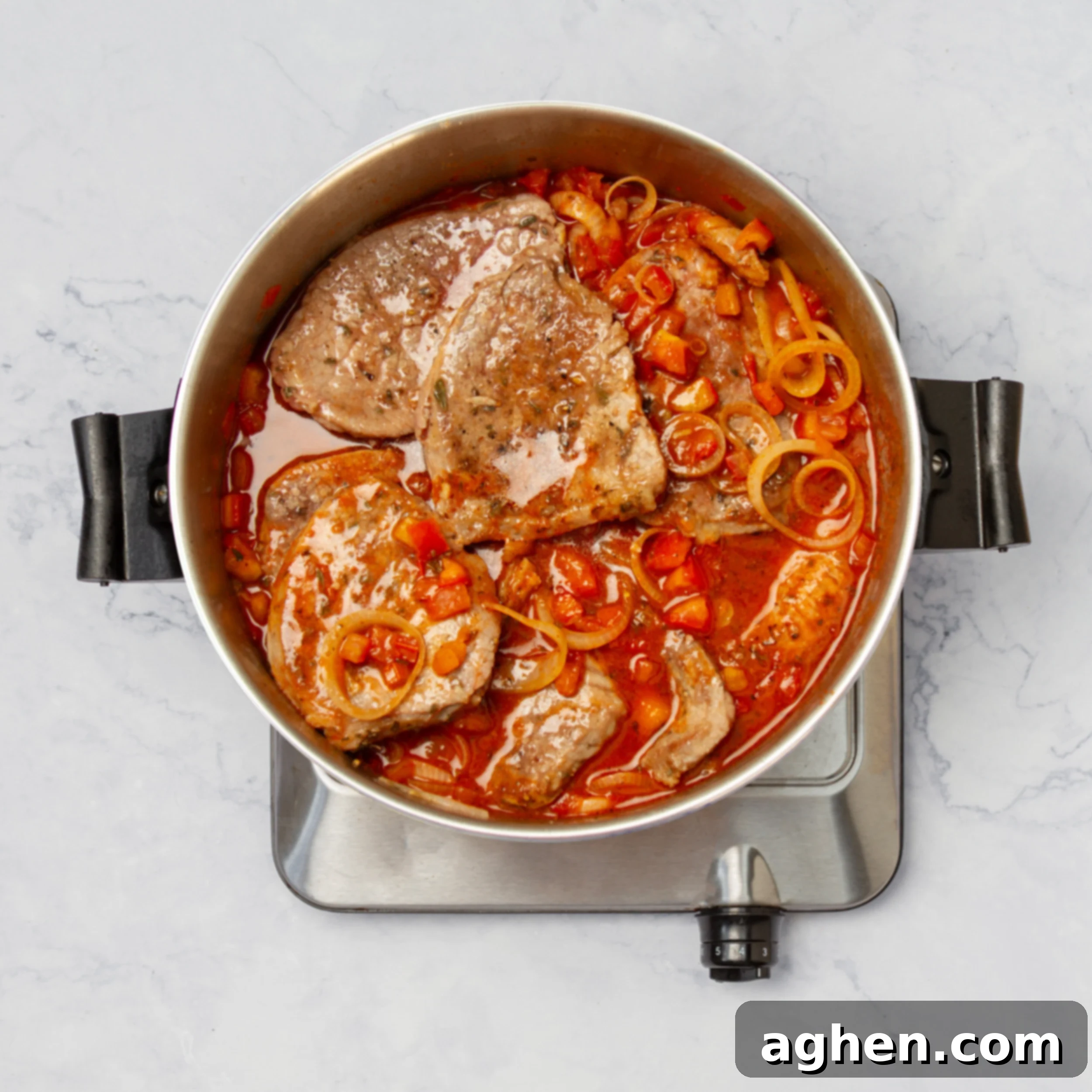 Seared beef steaks returned to the pot and submerged in the simmering tomato and vegetable sauce, ready for slow cooking to combine flavors.
