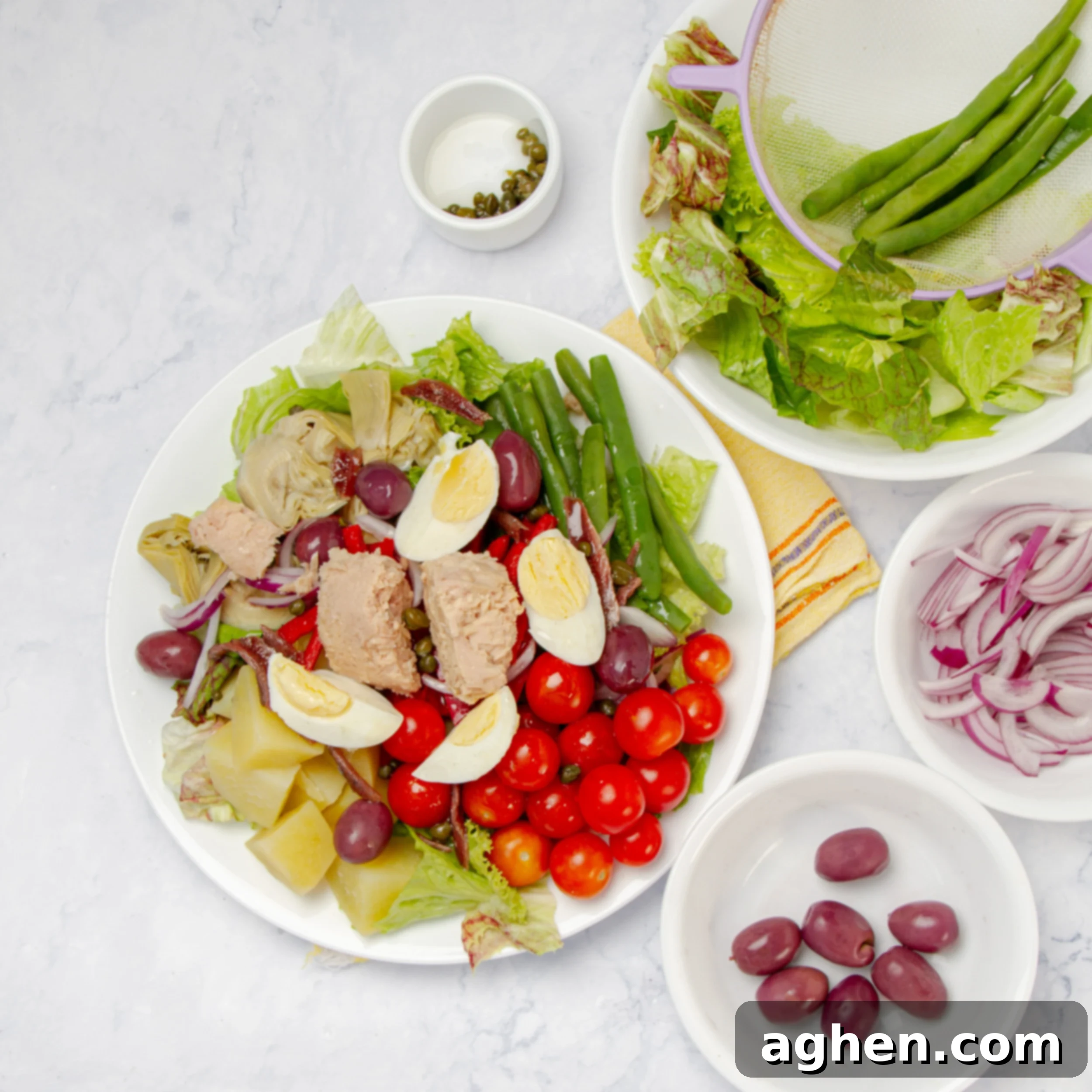All salad ingredients combined on a plate with extra olives and red onion on the side.