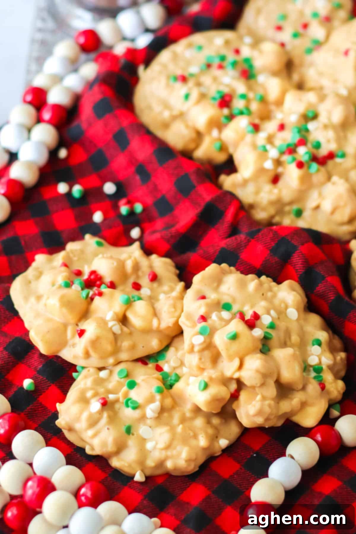 White chocolate, peanut butter, and marshmallow clusters topped with christmas sprinkles surrounded by holiday decor.