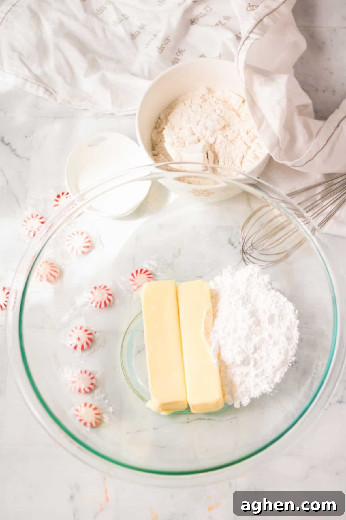 Softened butter and powdered sugar being mixed together in a large mixing bowl with an electric mixer.