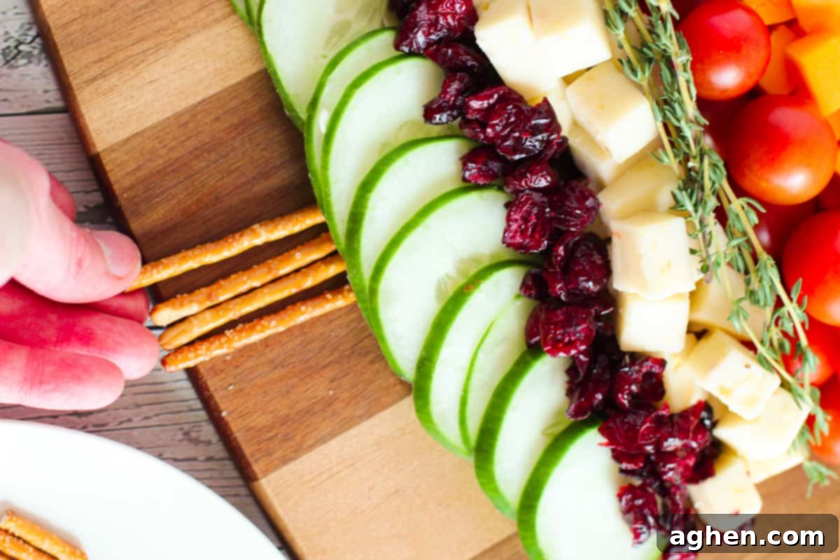 A hand meticulously arranging pretzel sticks at the base of the charcuterie tree, creating a sturdy and edible trunk.