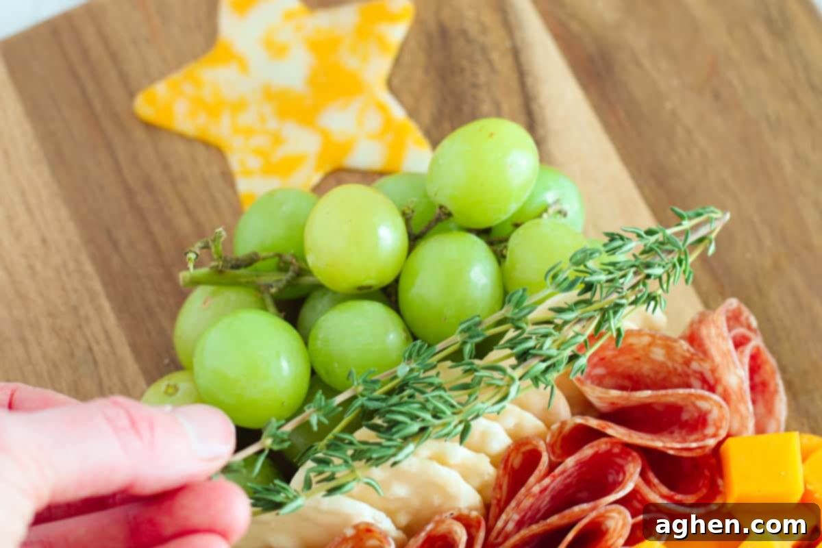 Fresh green grapes and sprigs of thyme artfully arranged on a Christmas tree charcuterie board, enhancing the festive appearance.