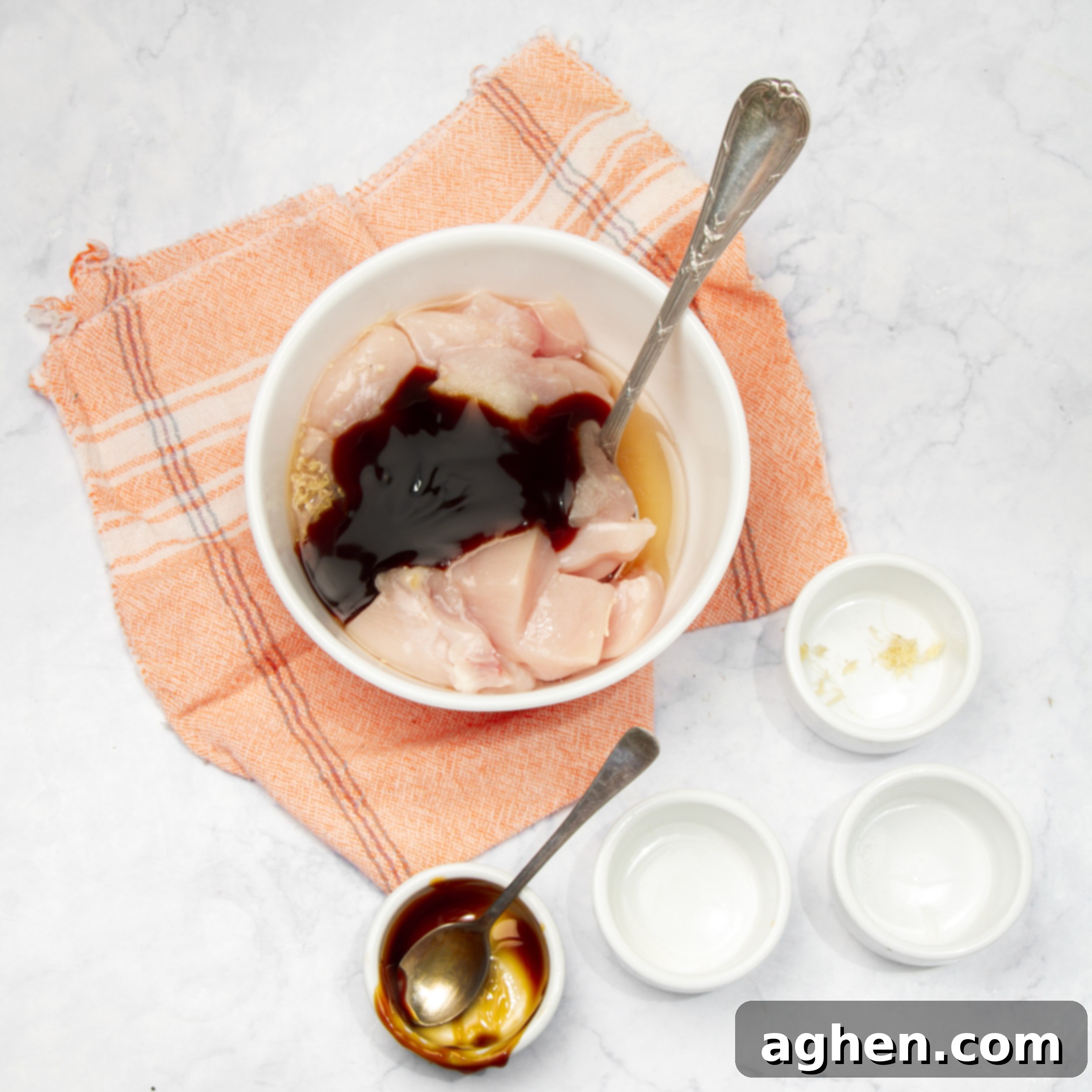 Raw chicken marinating in a small bowl. 