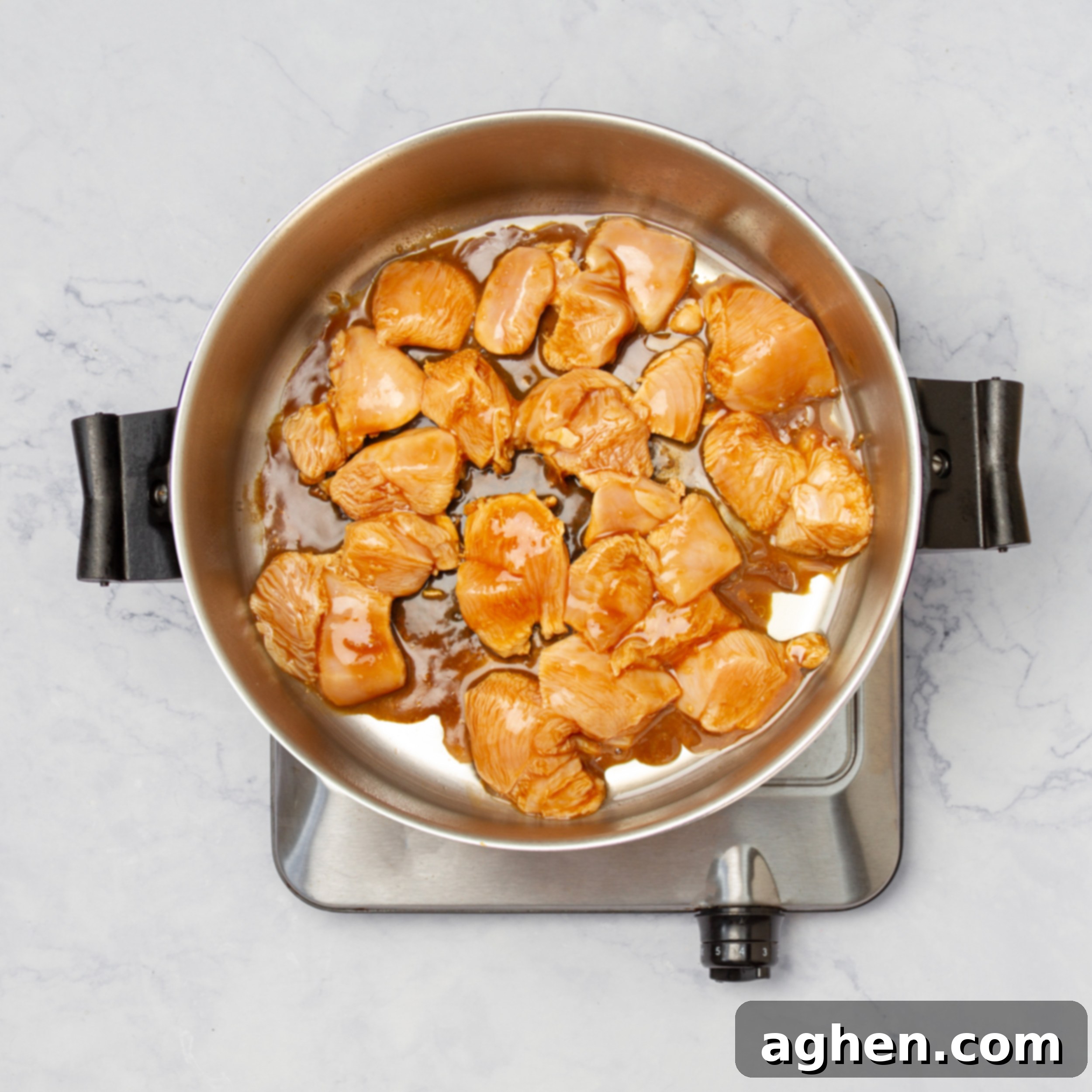 Chicken cubes browning in a hot pan. 