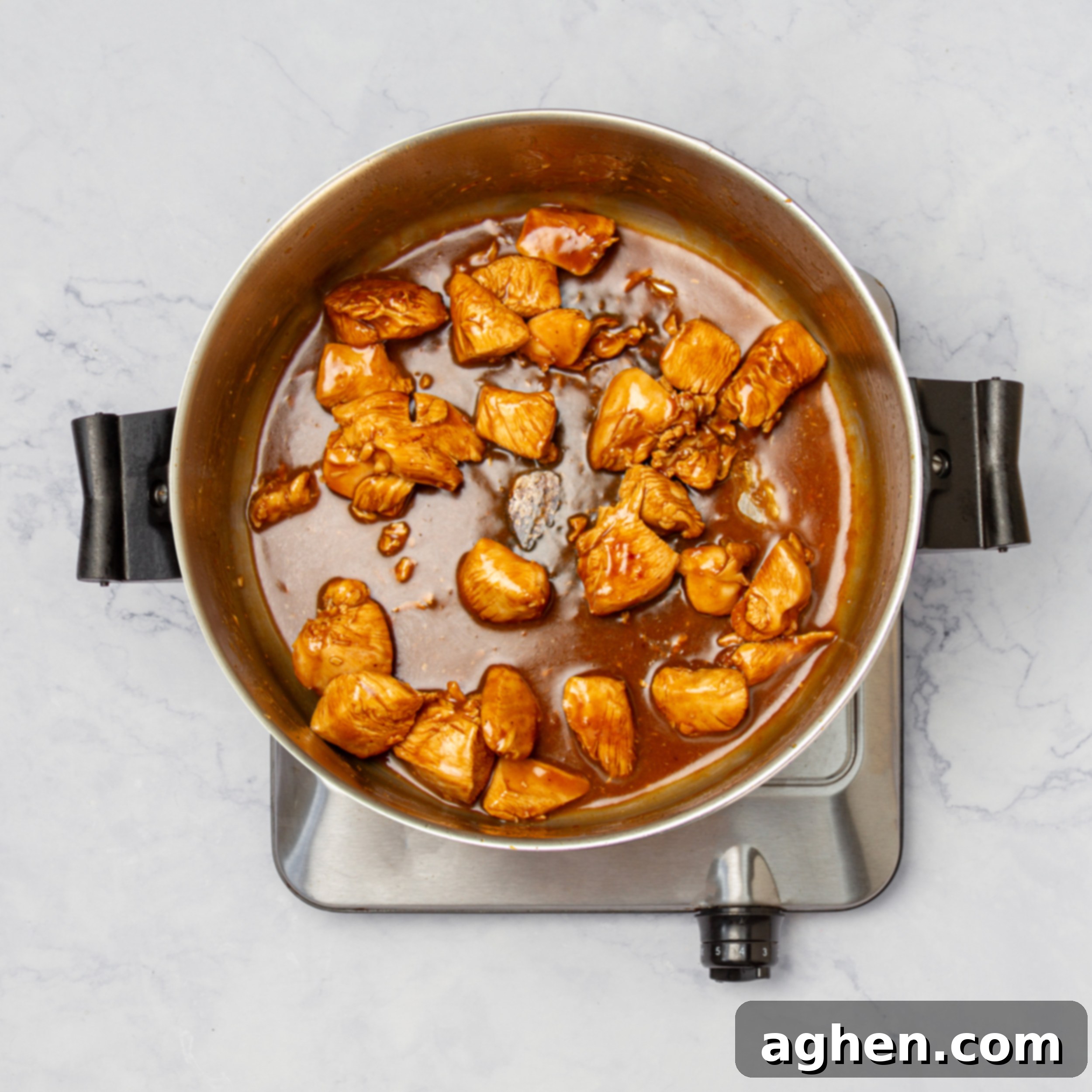 Thick glaze poured over the cooking chicken in the pan. 