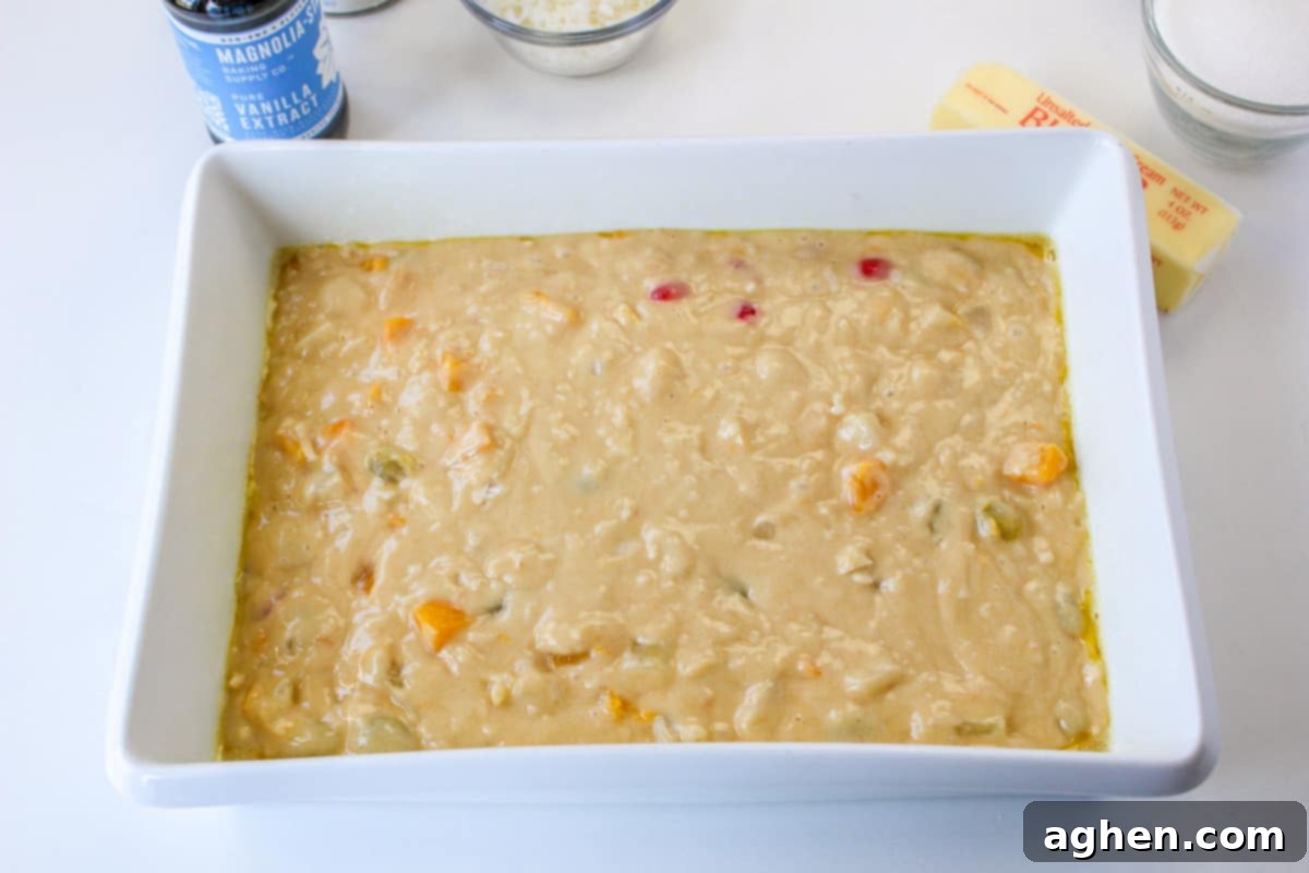 The fruit cocktail cake batter spread evenly in a greased 9x13 inch baking dish, ready for baking.