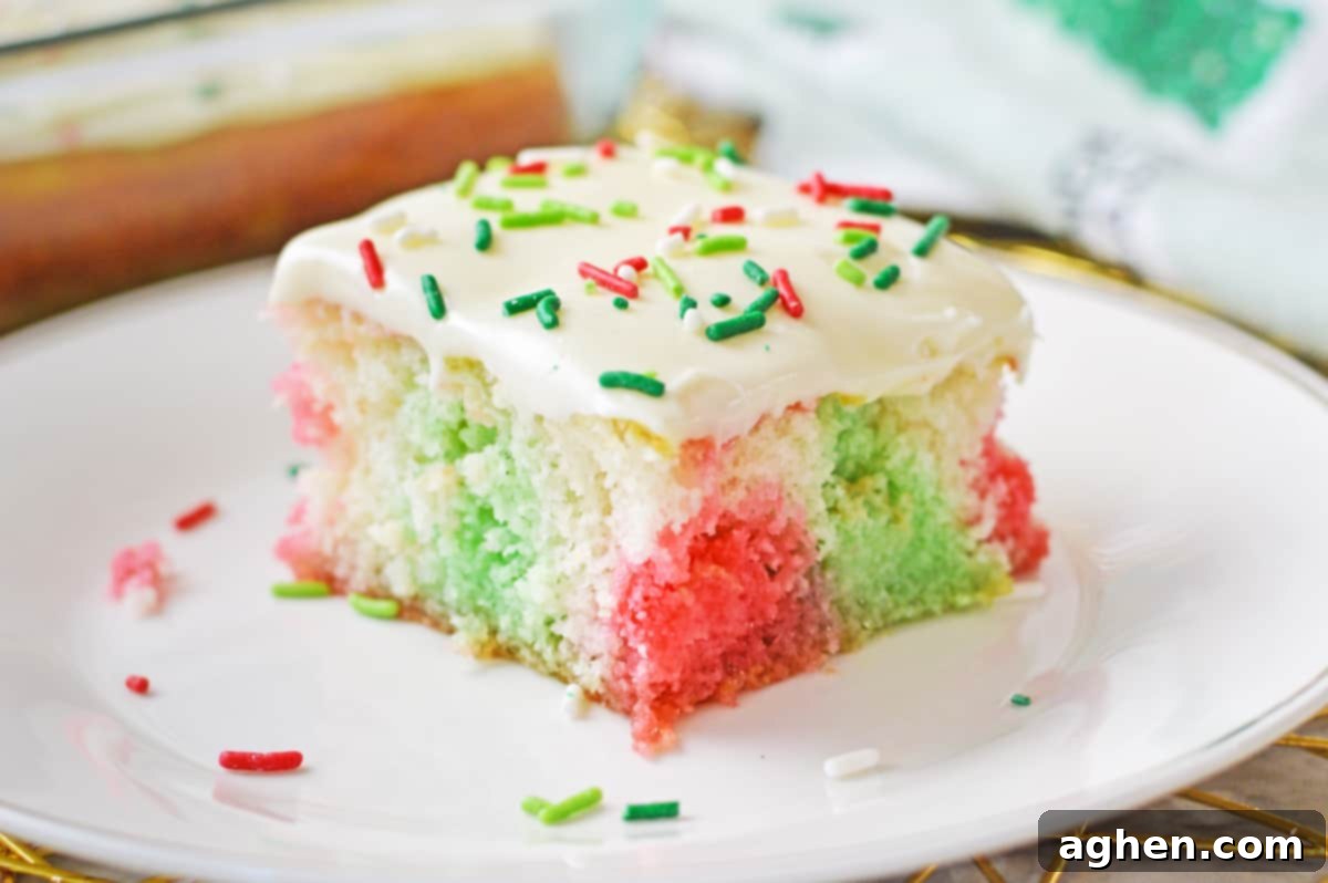 Square slice of jello poke cake with red and green jello injected throughout, revealing its vibrant and moist interior.