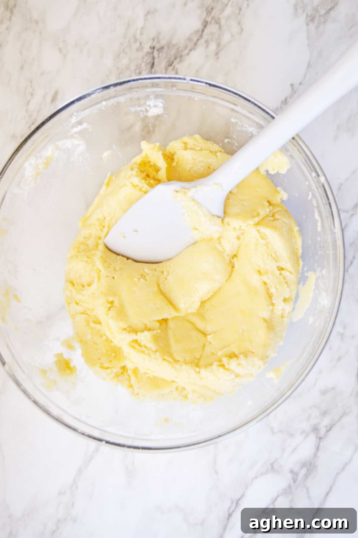 Cake mix cookie dough in glass mixing bowl with rubber spatula.