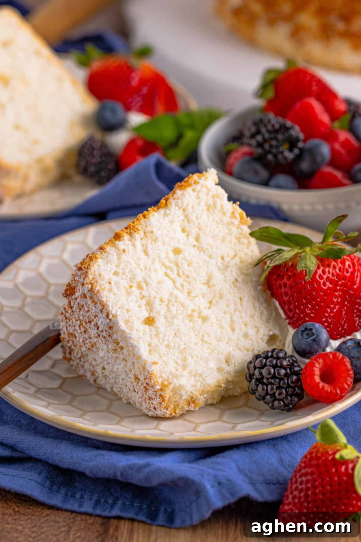 Slice of Angel Food Cake on white plate with fresh berries.