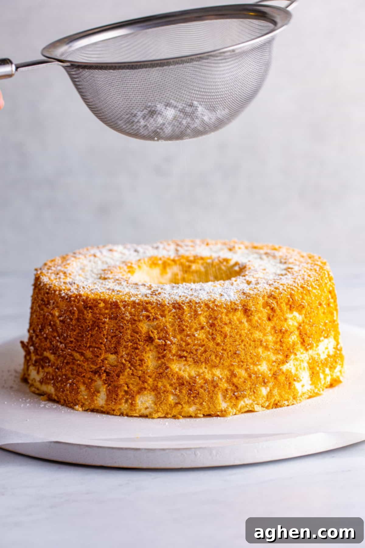 Powdered sugar being sifted on top of cooled cake.