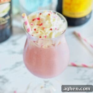 Pink strawberry mudslide in a glass with Kahlua and Baileys bottles behind it.