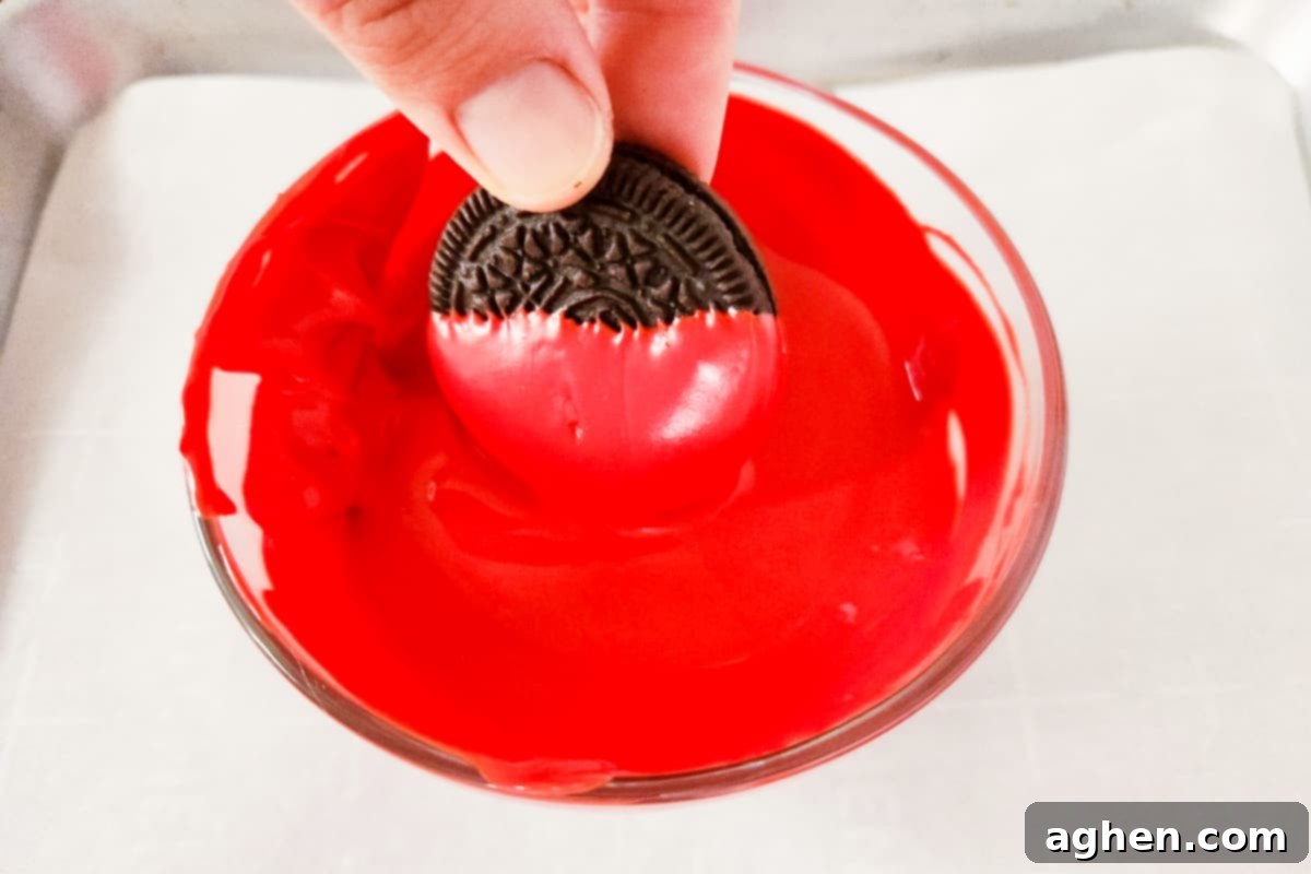 Oreo cookie being dipped in red melted candy.