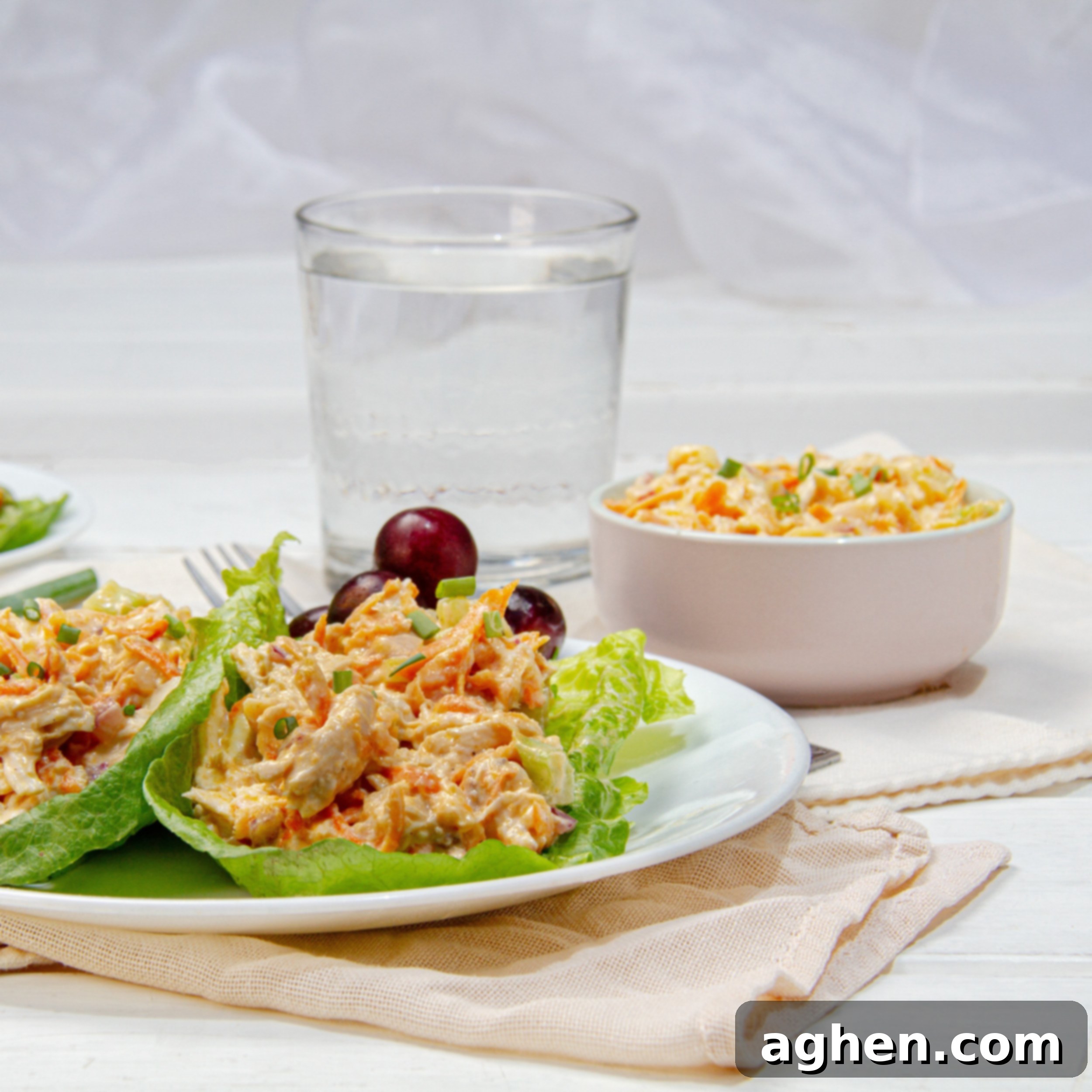 Deliciously Diet-Friendly Weight Watchers Buffalo Chicken Salad 2 Rich and creamy Buffalo Chicken Salad on a plate over lettuce wraps with water on the side, highlighting its vibrant color and appealing texture.