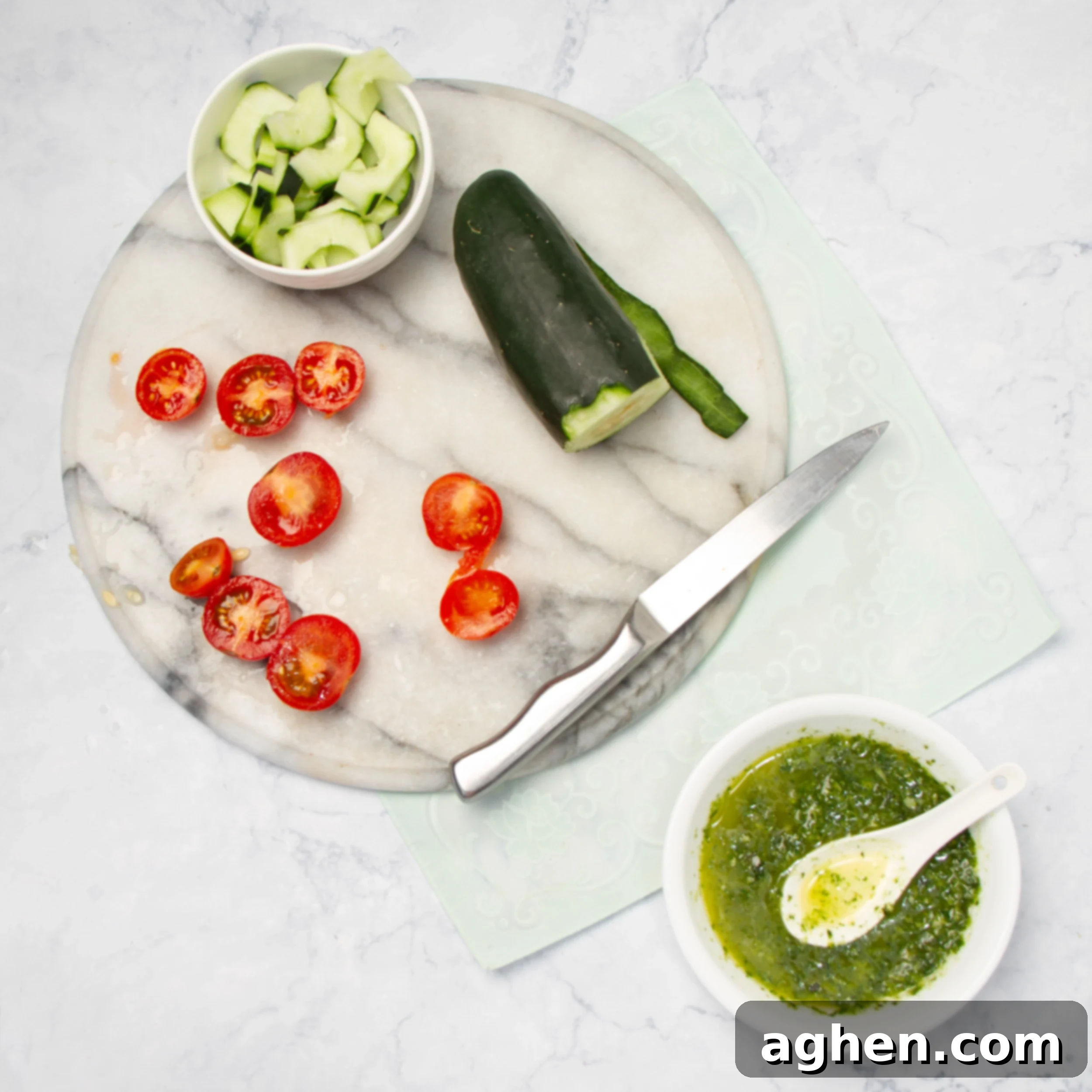 Pesto Chicken with Creamy Avocado 7 tomatoes and zucchini being cut on a small cutting board.