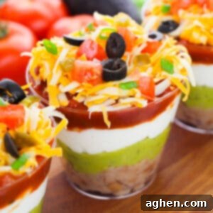 7 layer dip cups with refried beans, guacamole, sour cream, salsa, cheese, olives, green onions, tomatoes, and jalapenos.