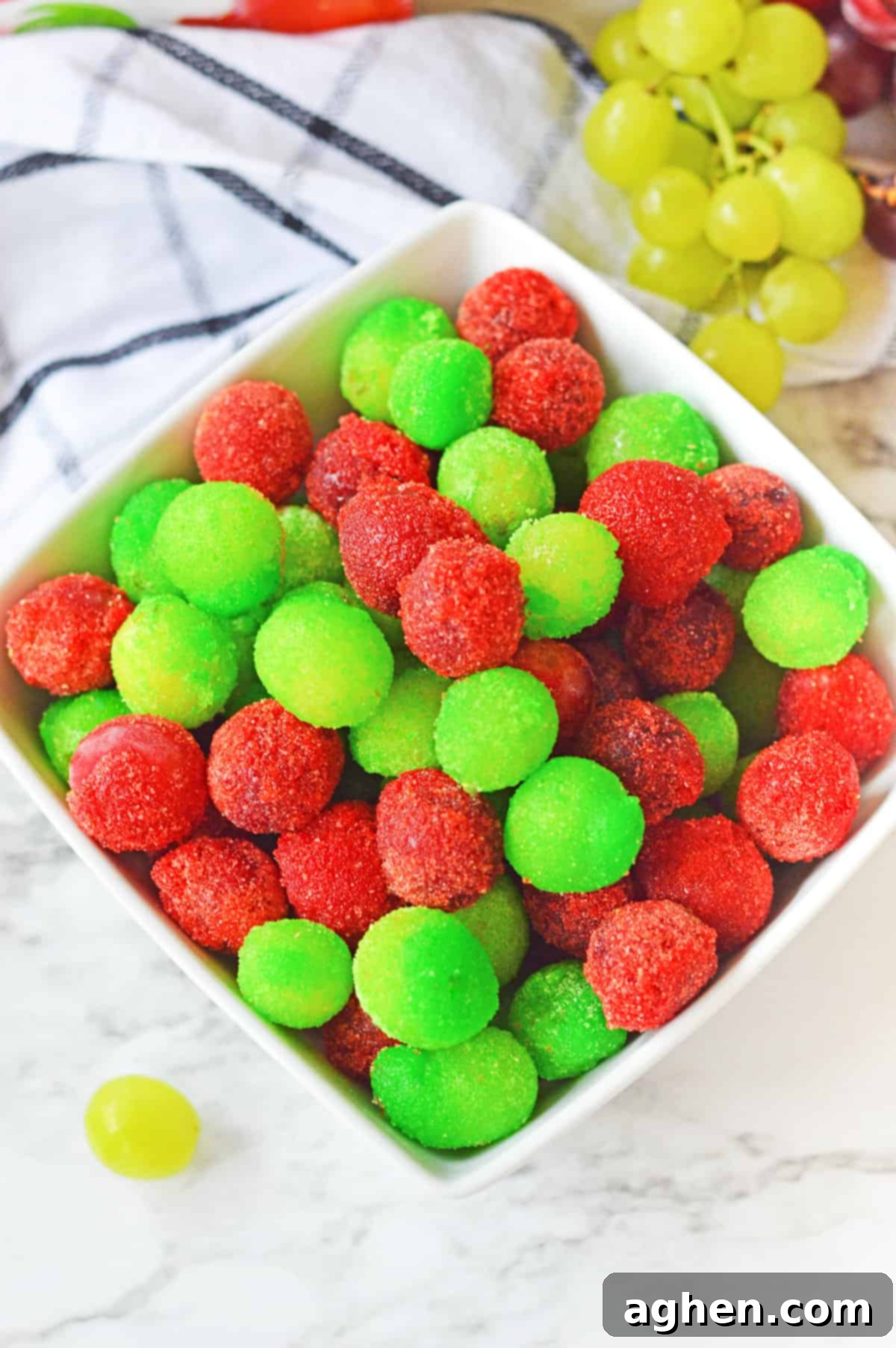 Overhead image of strawberry and green apple candied grapes in a white bowl.