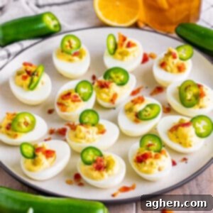 Fiery Deviled Egg Poppers 12 Jalapeno Popper Deviled Eggs with crispy bacon, cream cheese, and fresh jalapenos, arranged neatly on a white serving plate.