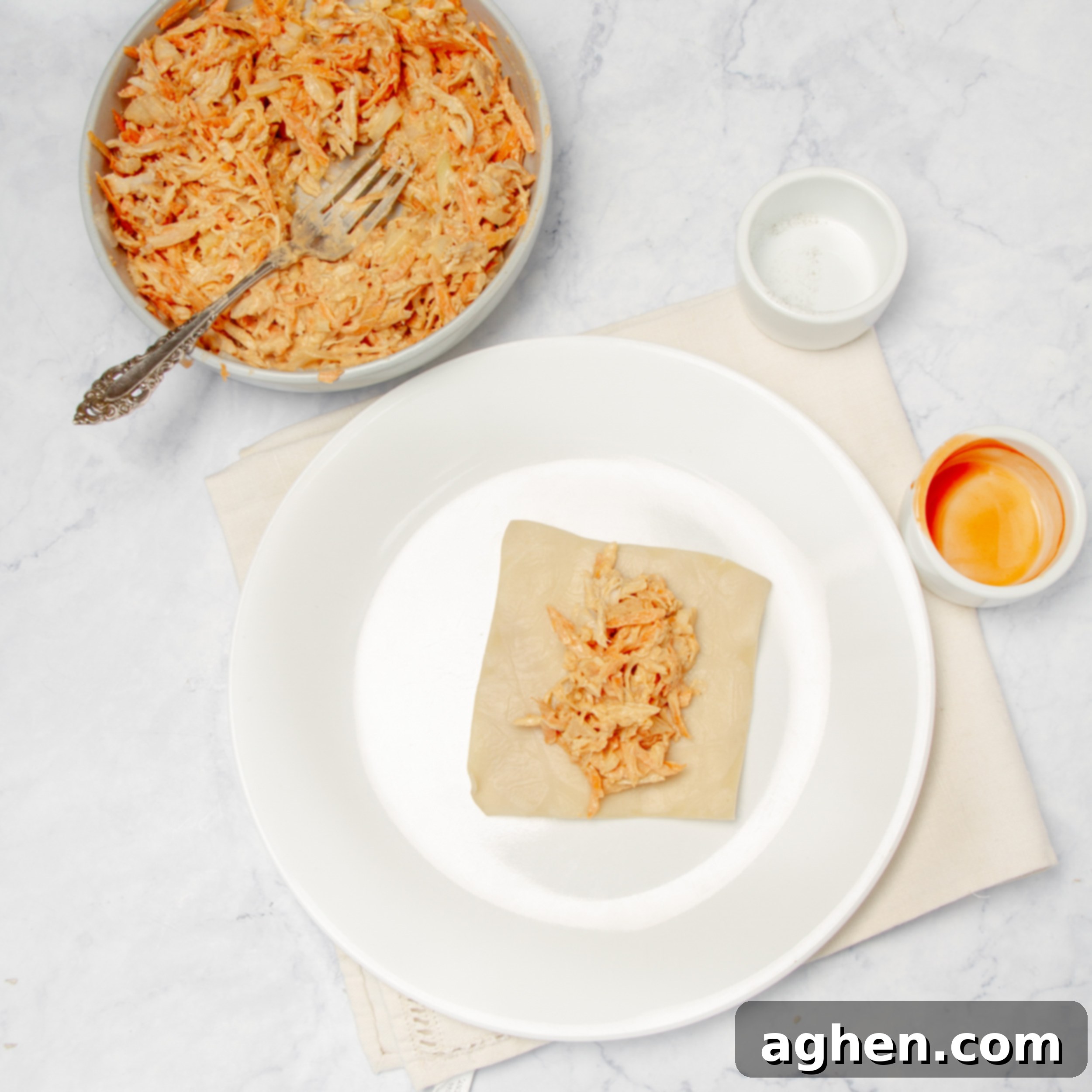 Filling added to a single egg roll wrapper on a plate. 