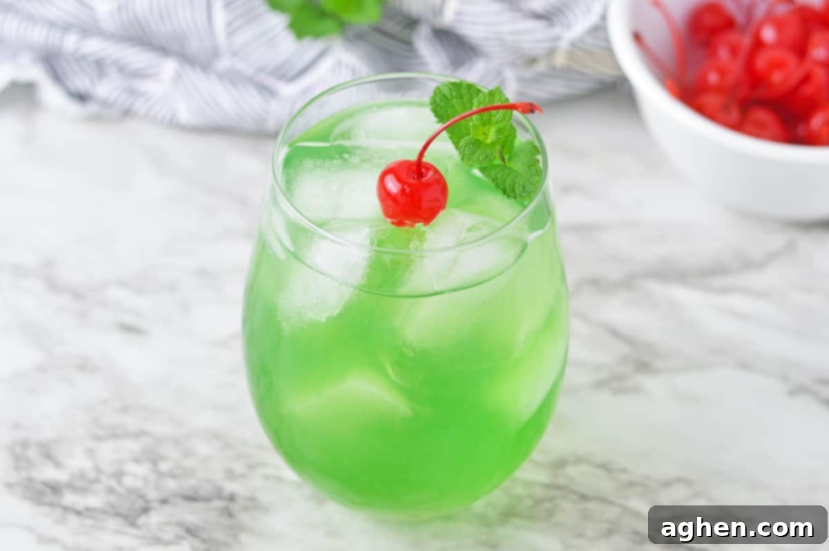 Green drink garnished with cherry and mint.