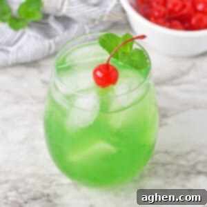 Luck of the Irish green cocktail topped with a cherry and sprig or mint.