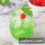 Luck of the Irish green cocktail topped with a cherry and sprig or mint.