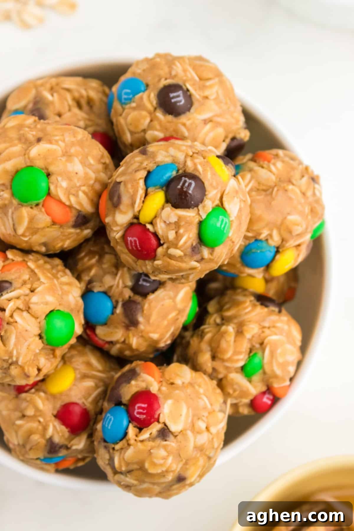 A bowl filled with a fresh batch of no-bake monster energy balls, showcasing the oats, chocolate chips, and colorful M&M's.