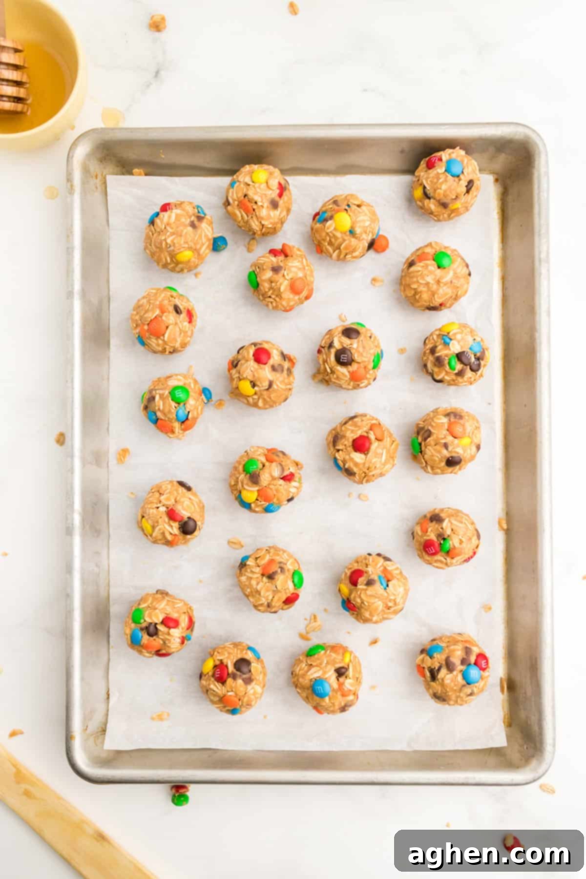 A baking sheet lined with parchment paper, holding perfectly rolled monster energy cookie balls, ready for chilling or serving.