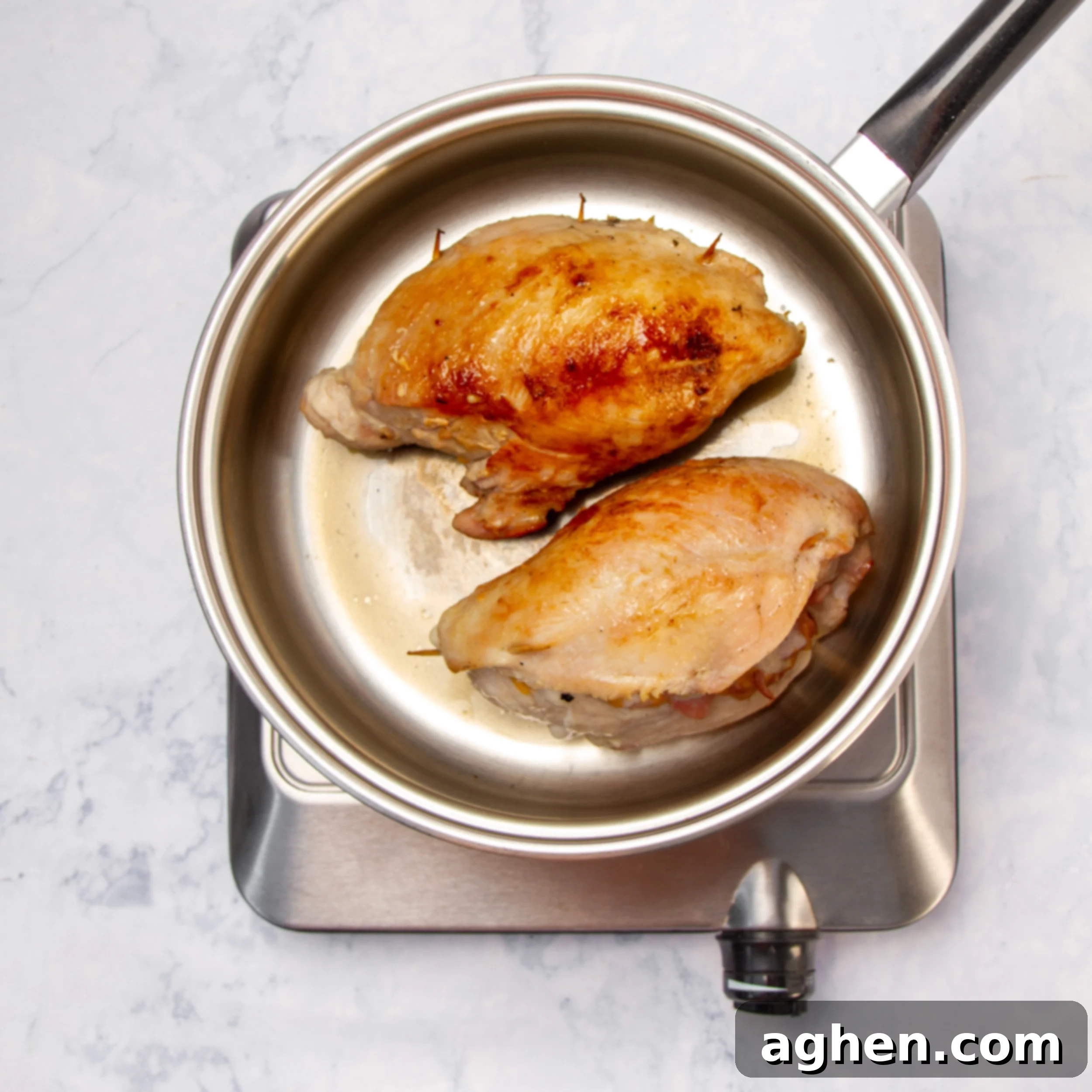 Elegant Stuffed Chicken Breast 5 Stuffed chicken breasts cooking in a hot pan.
