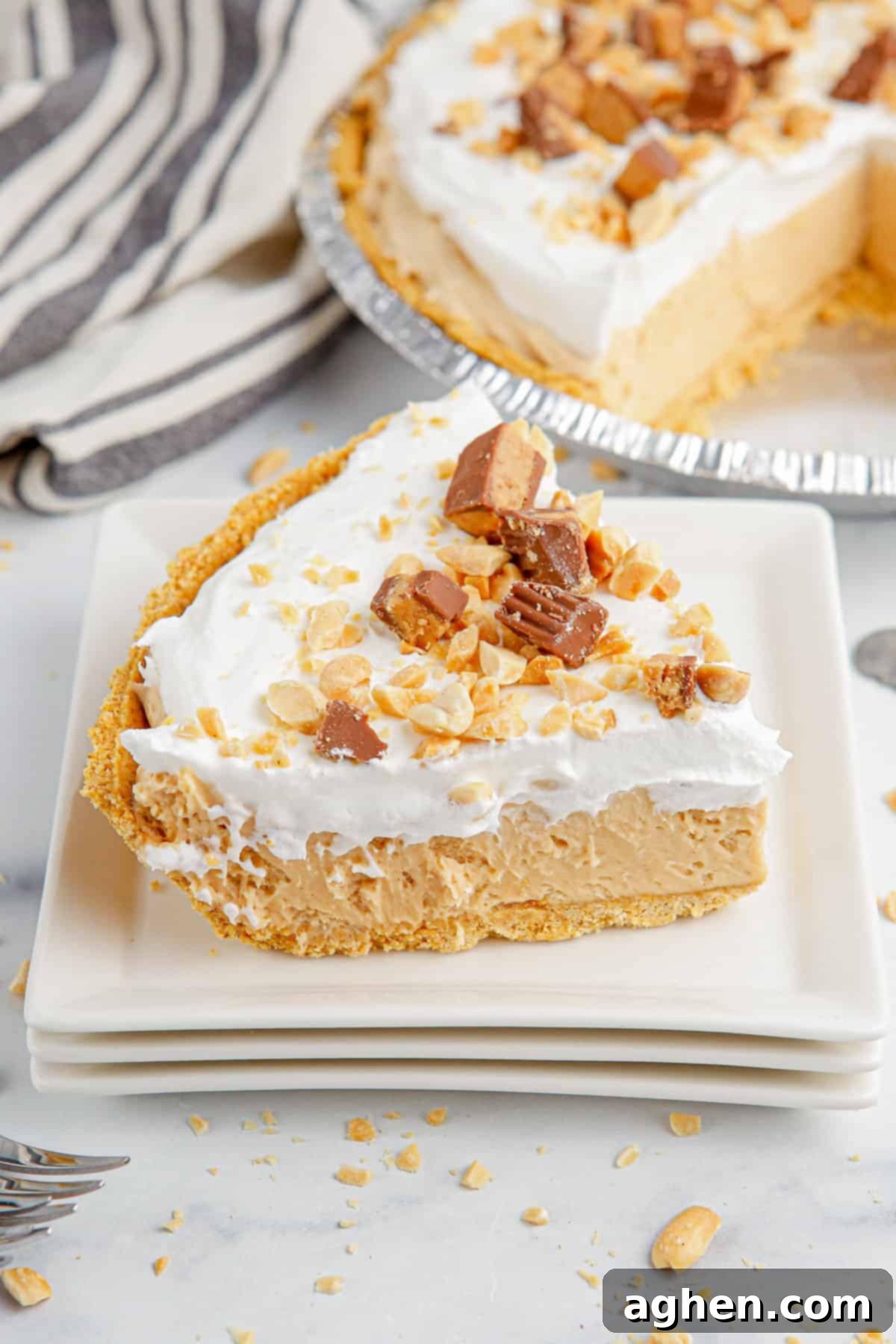 Slice of no bake peanut butter pie on a stack of square white plates, ready to be enjoyed.