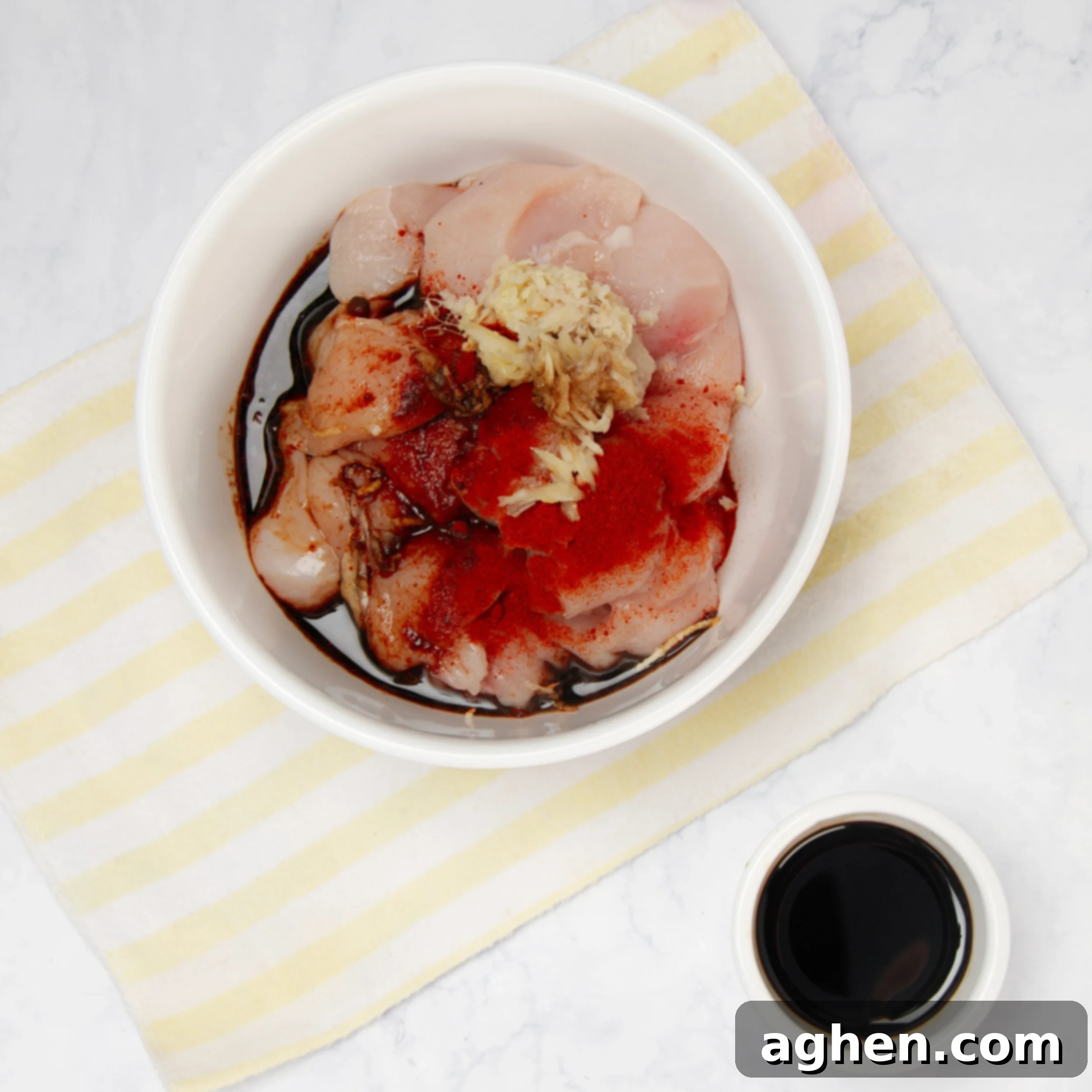 Raw chicken marinating in a small bowl. 