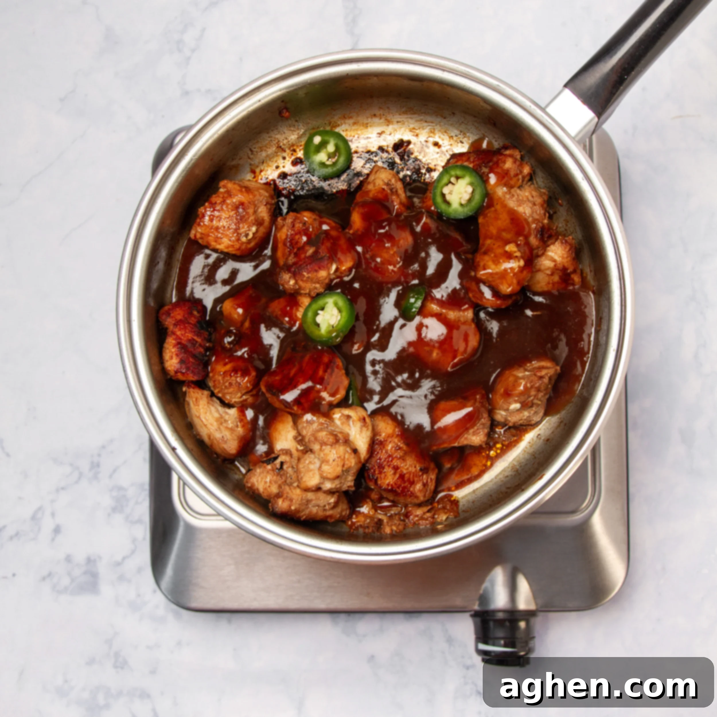 Cooked chicken chunks in the pan with General Tso's sauce. 