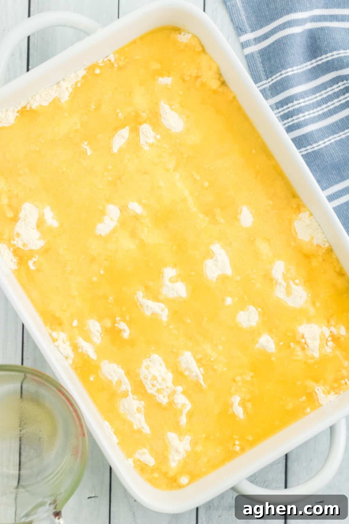 Melted butter generously poured over the top of the dry cake mix in the baking dish, creating a moist layer over the powder, with just a few small spots of dry mix visible.