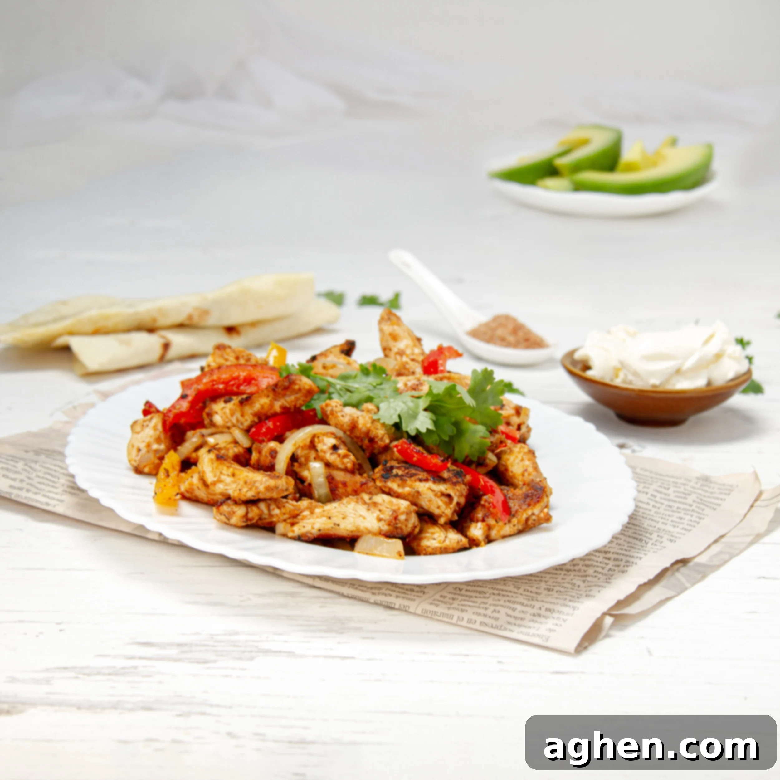 Guilt-Free Chicken Fajitas 2 Sizzling healthy chicken fajitas on a plate with fresh cilantro garnish and avocado slices, tortillas, and sour cream on the side.