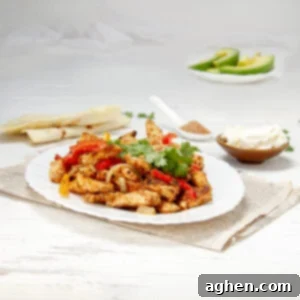 Guilt-Free Chicken Fajitas 8 Sizzling healthy chicken fajitas on a plate with fresh cilantro garnish and avocado slices, tortillas, and sour cream on the side.