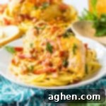 Slow cooker marry me chicken breasts with creamy sun-dried tomato sauce and fresh basil over spaghetti.