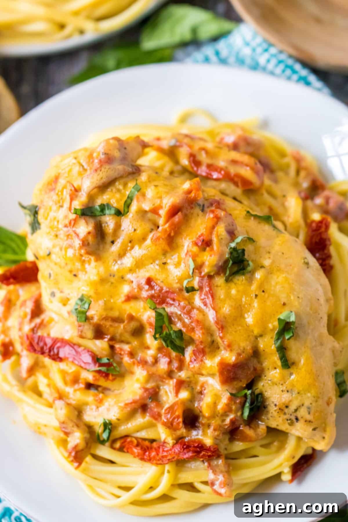 Slow Cooker Marry Me Chicken garnished with fresh basil and served over spaghetti.