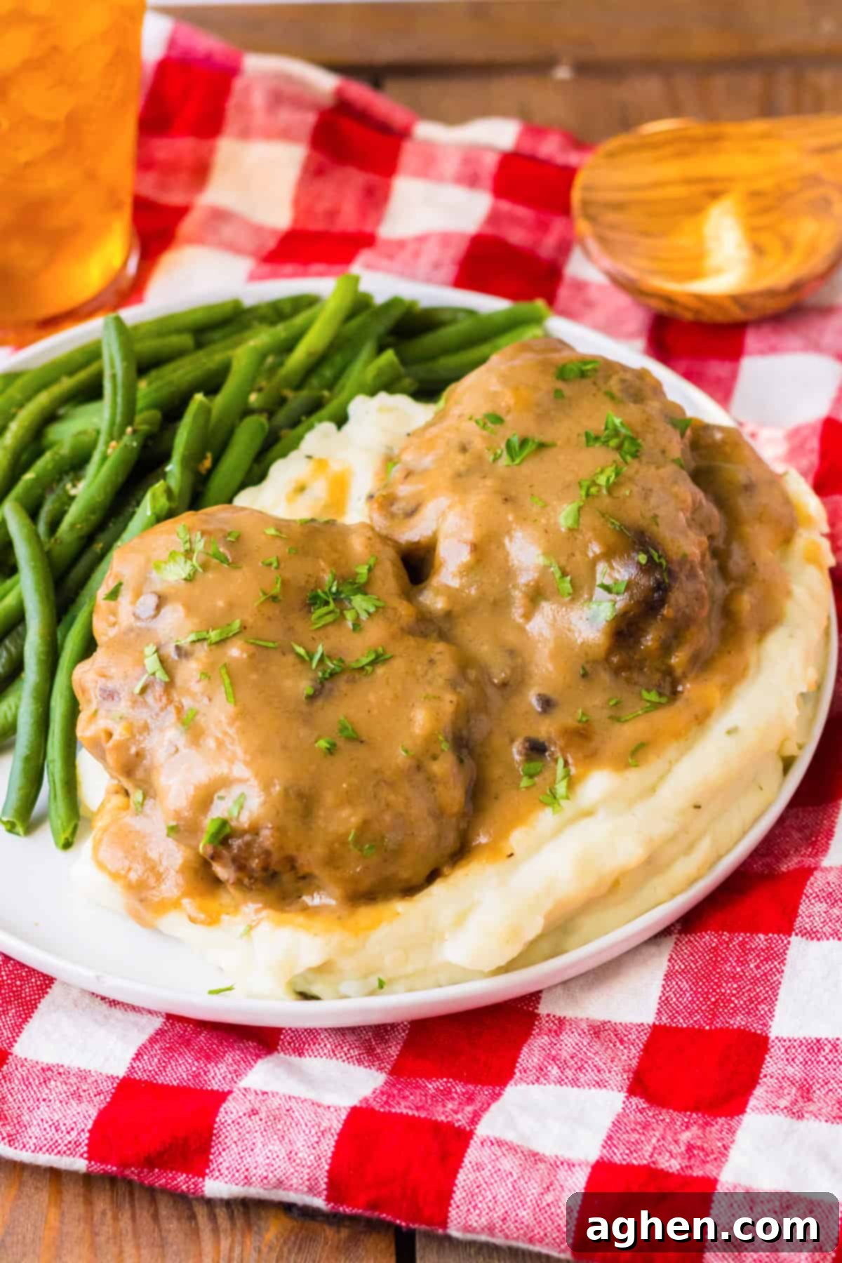 Easy Slow Cooker Salisbury Steaks 2 Slow cooker salisbury steaks smothered with rich brown gravy over a bed of mashed potatoes and served with a side of string beans.