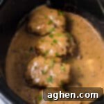 Easy Slow Cooker Salisbury Steaks 12 Slow cooker salisbury steaks smothered with brown gravy and garnished with parsley in a crockpot.
