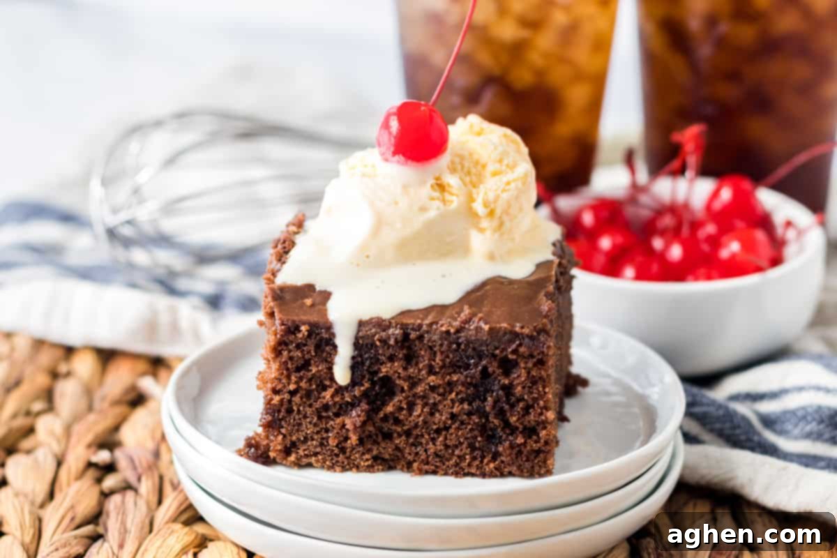 Decadent Double Chocolate Coca Cola Cake 10 A perfectly square slice of rich double chocolate Coca-Cola cake, generously covered with dark chocolate frosting, and adorned with a scoop of melting vanilla ice cream and a vibrant cherry on top. This image highlights the luscious texture and appealing presentation of the Cracker Barrel copycat dessert.