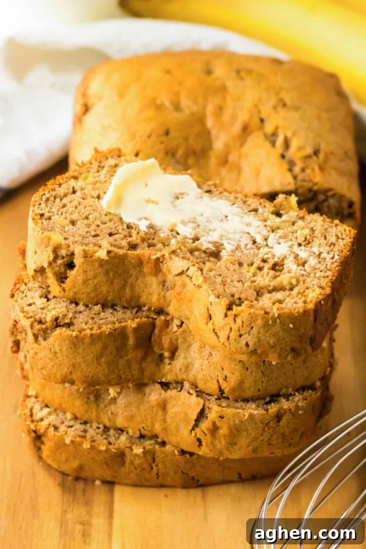 Stack of sliced easy cake mix banana bread, the top slice with butter.