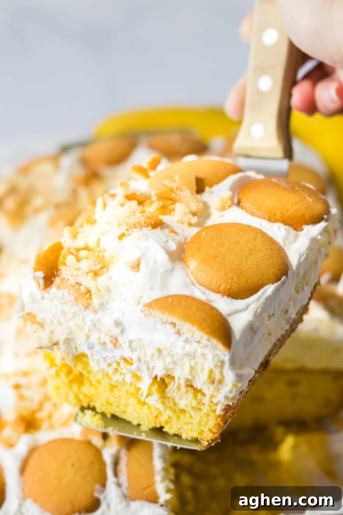 Banana Cream Dream Poke Cake 11 A perfectly portioned slice of banana pudding poke cake is gently lifted from the baking dish with a spatula, revealing its moist cake layers and rich, creamy banana pudding filling.