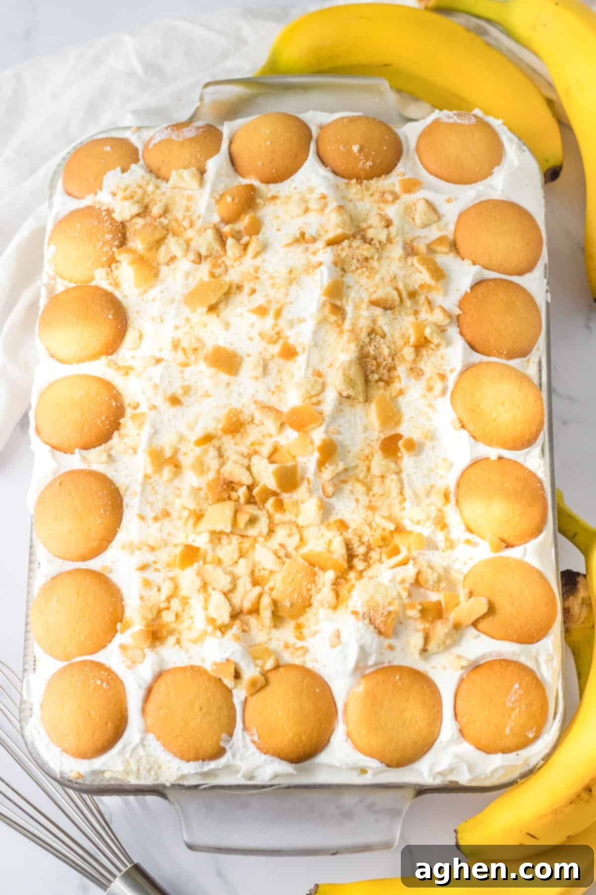 Banana Cream Dream Poke Cake 9 A beautifully finished poke cake, generously topped with a smooth layer of whipped cream. Whole vanilla wafers are artfully arranged around the perimeter, creating an appealing border, while crushed vanilla wafer crumbs are scattered in the center for added texture and classic banana pudding visual appeal.