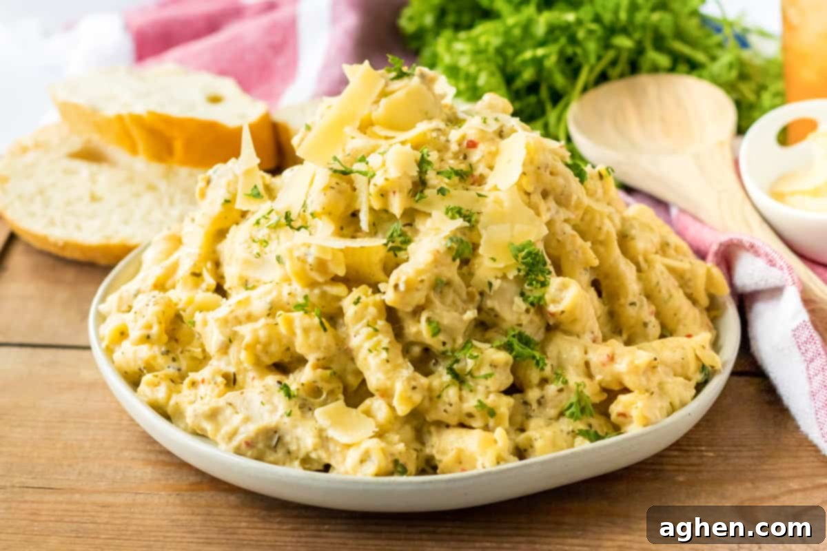Creamy Crockpot Garlic Parmesan Chicken Pasta 8 Crockpot parmesan garlic chicken pasta served on a white plate with fresh parsley and bread.