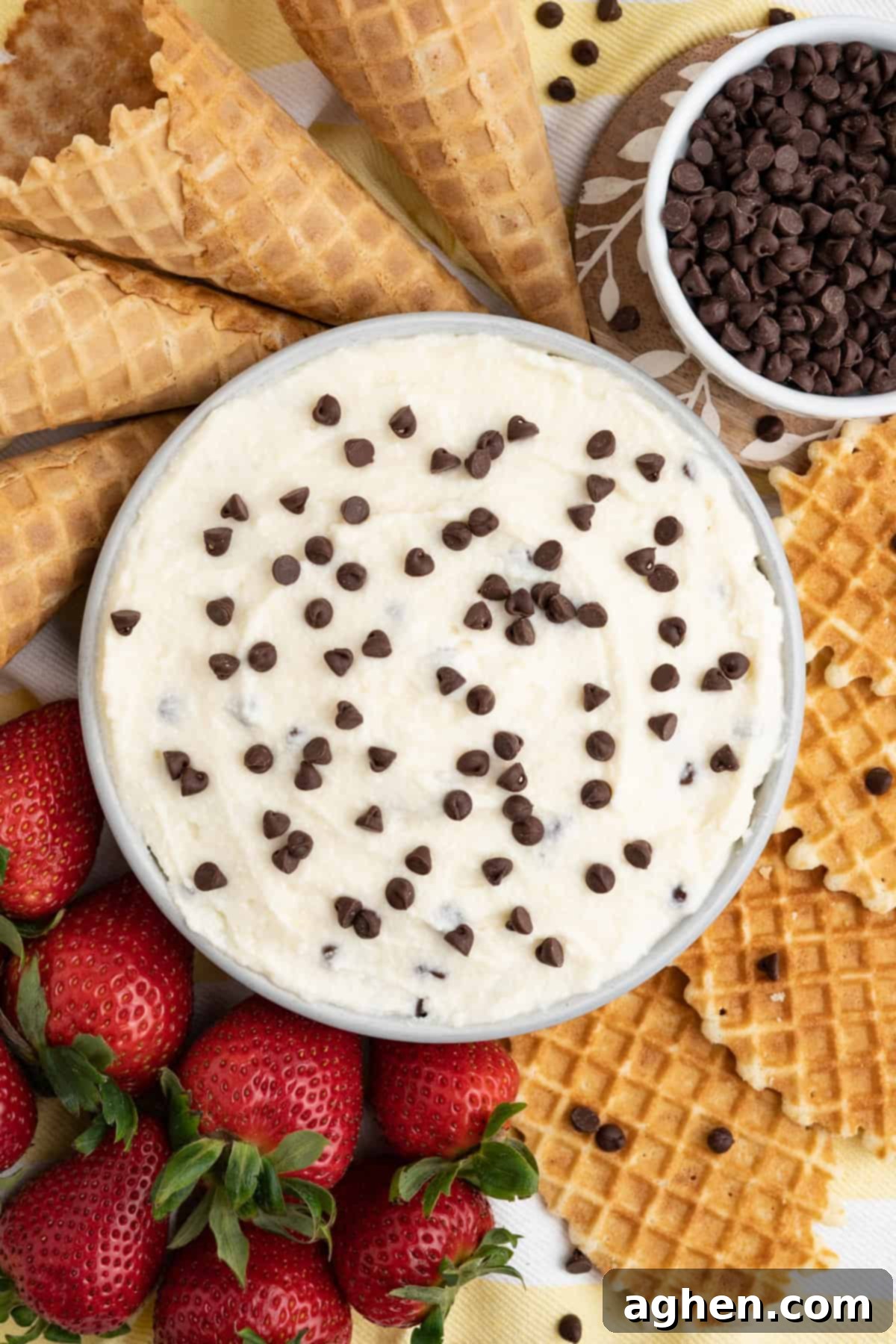 Creamy cannoli dip topped with mini chocolate chips and served with waffle cookies, ice cream cone pieces, and strawberries, perfect for a quick and easy dessert.